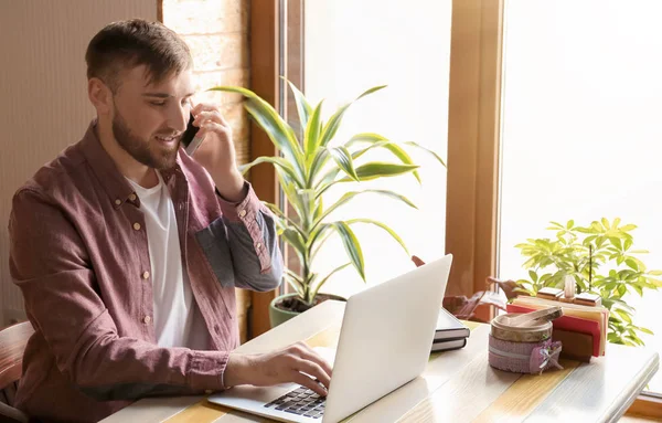 Joven Freelancer Hablando Por Teléfono Móvil Mientras Trabaja Ordenador Portátil —  Fotos de Stock