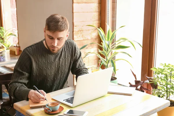 Dizüstü bilgisayar ve notebook kafede çalışan genç serbest meslek