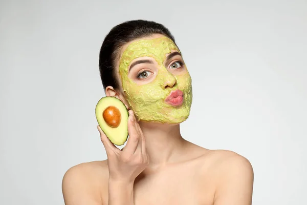 Hermosa Joven Con Máscara Facial Aguacate Fresco Sobre Fondo Claro —  Fotos de Stock