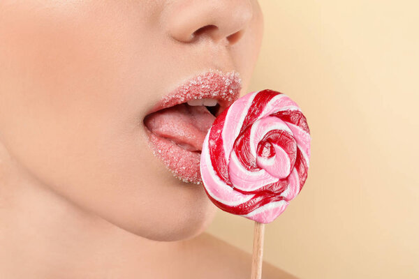 Красивая молодая женщина с творческим макияжем и леденец на цветном фоне, крупным планом

