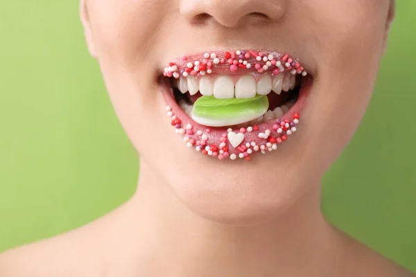 美丽的年轻妇女与创造性的化妆和糖果在嘴上的颜色背景 — 图库照片