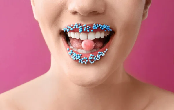 美丽的年轻妇女与创造性的化妆和糖果在嘴上的颜色背景 — 图库照片