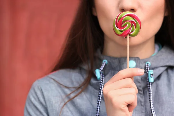 Attractive young woman with lollipop on blurred background, closeup