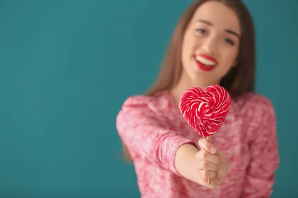 Attractive young woman with lollipop on color background