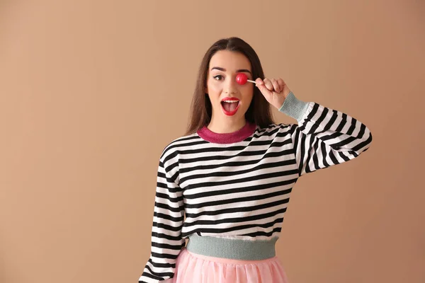 Attractive young woman with lollipop on color background