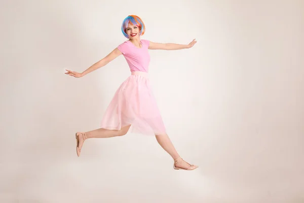Saltando Mujer Joven Con Pelo Colorido Contra Pared Luz — Foto de Stock