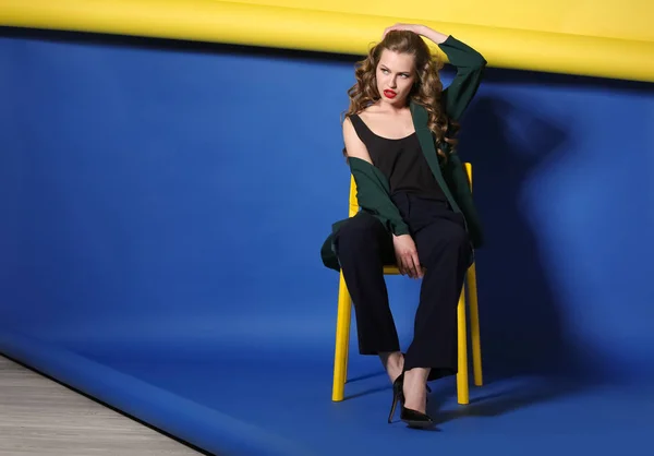色背景に椅子に座って美しい若い女性 — ストック写真