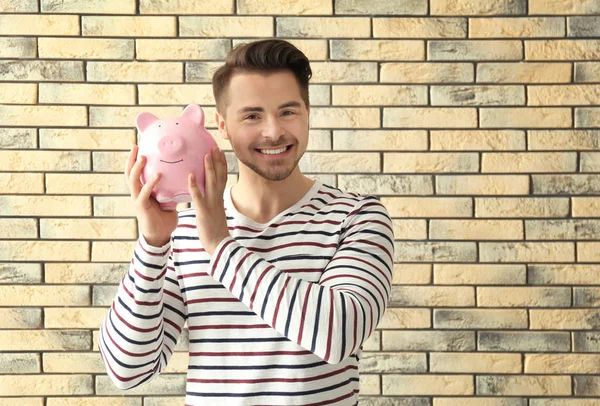 Young Man Holding Piggy Bank Brick Background Savings Money Concept — Stock Photo, Image