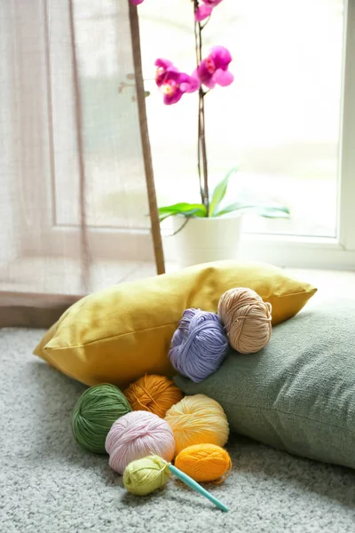 Colorful knitting yarns and crochet on carpet indoors