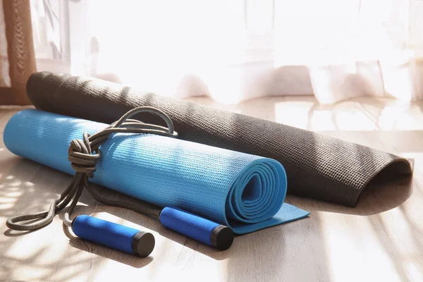 Yoga mats and jump rope on wooden floor
