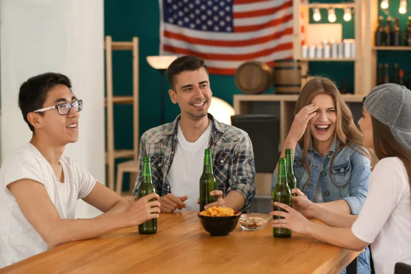 Group of cheerful friends drinking beer in bar