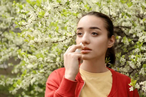 Mujer Joven Que Usa Gotas Nasales Cerca Del Árbol Flor —  Fotos de Stock