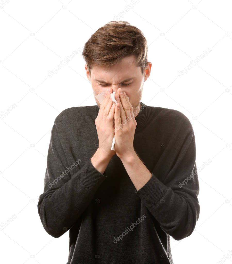 Young man with nose wiper on white background. Allergy concept