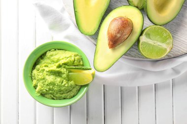 Lezzetli guacamole ve ahşap masa üzerinde olgunlaşmış avokado ile kase