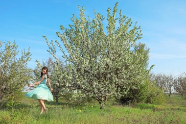 Güneşli bahar gününde çiçek açması tree yakınındaki güzel genç kadın