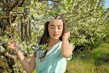 Güneşli bahar gününde çiçek açması tree yakınındaki güzel genç kadın