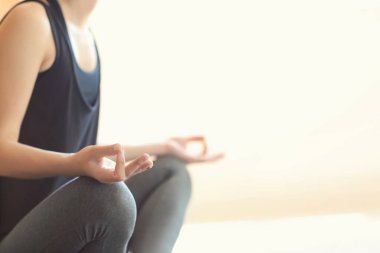 Genç kadın arka planda yoga yapıyor.