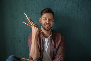 Renk arka plan üzerinde boyama araçlarıyla erkek sanatçı