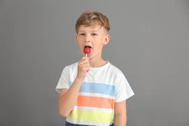 Sevimli küçük çocuk gri arka plan üzerinde lolipop yemek