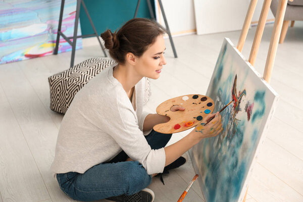 Female artist painting picture in workshop