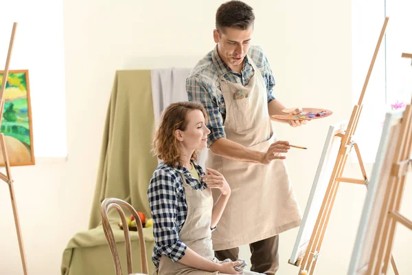 Male teacher helping his student during classes in school of painters