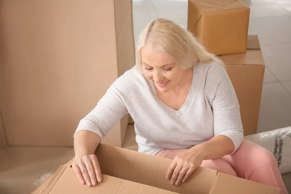 Mature woman unpacking moving box at new home