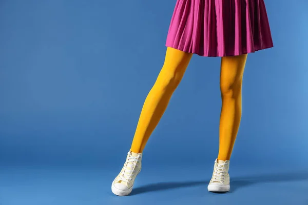 美丽的年轻女子的腿穿着紧身衣和裙子在颜色背景 — 图库照片