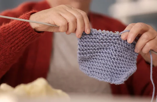 Senior woman knitting warm sock at home