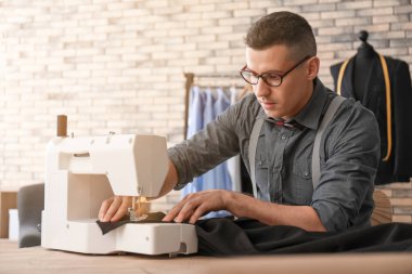 Atelier dikiş makinesi üzerinde çalışan genç terzi