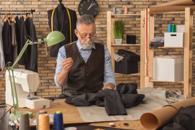 Olgun terzi atölyesi masada dikiş
