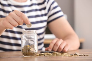 Paralar cam kavanozun içine masanın üzerine koyarak adam. Tasarruf kavramı