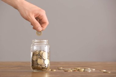Paralar cam kavanozun içine masanın üzerine koyarak adam. Tasarruf kavramı