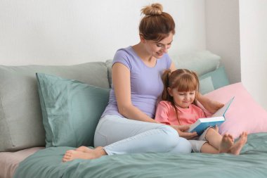 Anne ve kızı evde birlikte kitap okuma