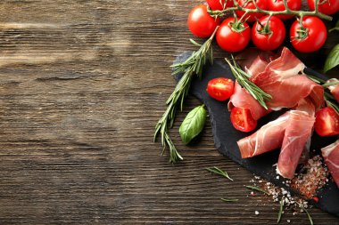 Kayrak kurulu ile lezzetli salam dilimleri, domates, baharatlar ve otlar ahşap tablo