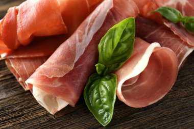 Lezzetli salam dilimleri üzerinde ahşap masa, closeup fesleğen ile