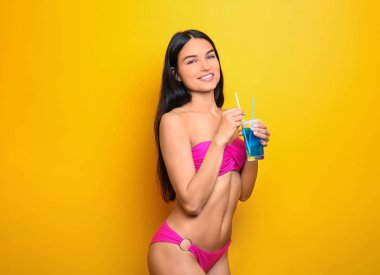 Güzel genç kadın bikini ve renk arka plan üzerinde içki ile