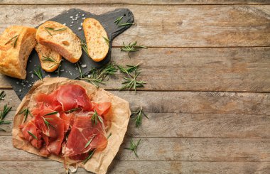 Prosciutto biberiye ve ekmek ile ahşap masanın üzerine dilimlenmiş