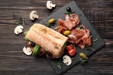 Prosciutto ile zeytin ve kayrak plaka üzerinde fesleğen ile lezzetli sandviç