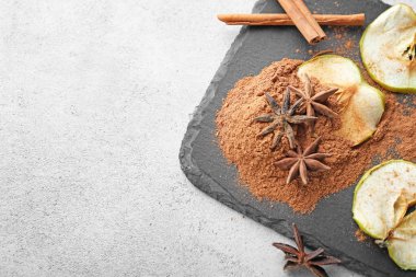 Kayrak plaka toz tarçın ve açık renkli kurutulmuş elma dilimleri ile