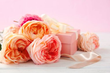 Güzel çiçek ve hediye kutusu ahşap masa renk arka plan üzerinde