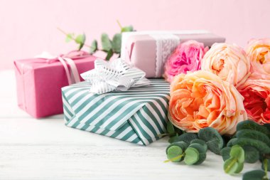 Güzel çiçek ve hediye kutuları ahşap masa renk arka plan üzerinde