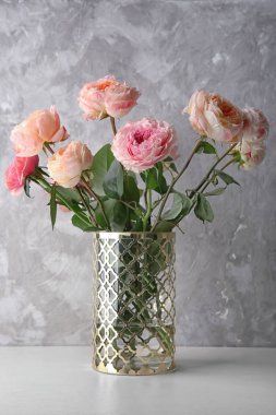 Vazo ile gri dokulu arka plan karşı masada güzel gül buketi