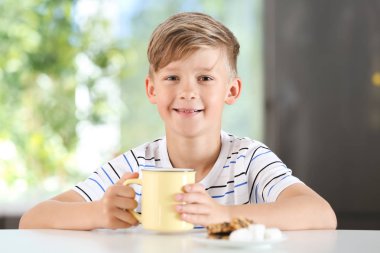 Masada sıcak kakao içecek fincan ile şirin küçük çocuk