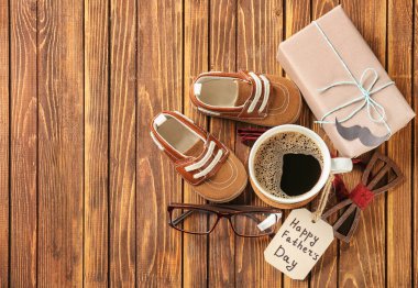 Hediye kutusu, fincan kahve, erkek aksesuarları ve ahşap arka plan bebek ayakkabıları. Mutlu babalar günü kutlama