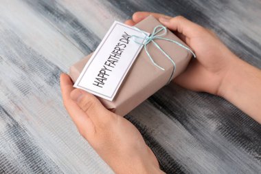 Hediye kutusu ile mutlu babalar günü kartı ahşap arka plan üzerinde tutan adam