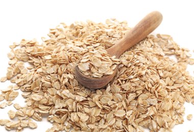 Kaşık ve beyaz arka plan üzerinde çiğ yulaf ezmesi yığını