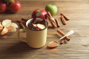 Tarçın ve ahşap masa üzerinde elma ile çay bir fincan