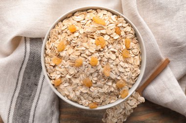 Yulaf gevreği ve ahşap masa üzerinde kuru üzüm ile kase