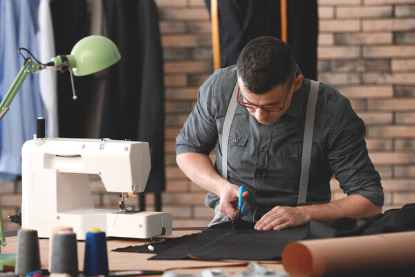 Молодой портной режущей ткани в ателье
