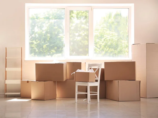 Carton boxes and interior items on floor in room. Moving house concept